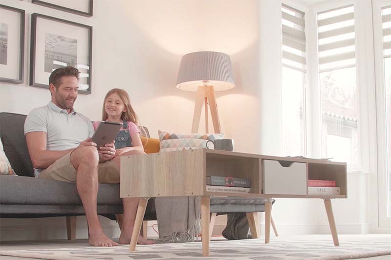 man and daughter using smart device to control blinds in living room